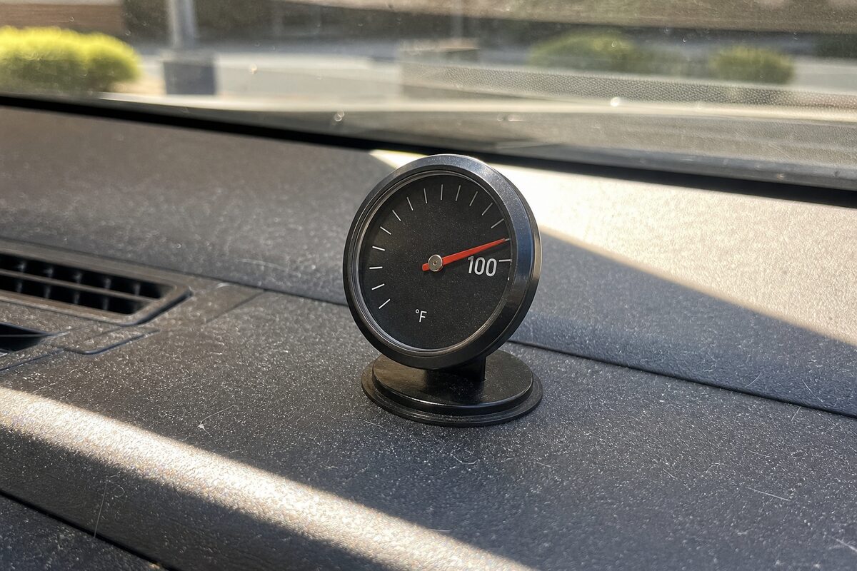 Car dashboard thermometer reading over 100 degrees in direct afternoon sun